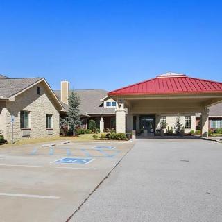 A building with a red-roofed entrance and adjacent parking lot under a clear blue sky.