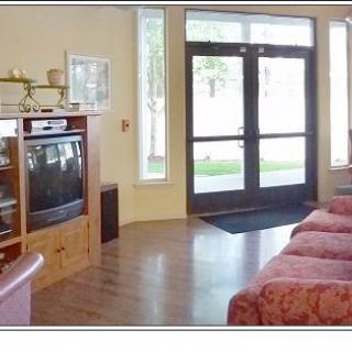 A cozy living room with a television, couch, and wooden flooring leading to a glass doorway.