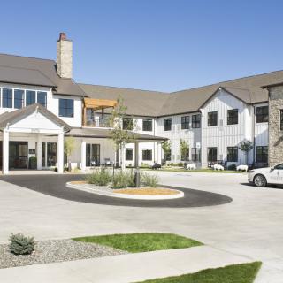 A modern residential building with a circular driveway and landscaped areas.