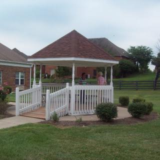 A white gazebo surrounded by a well-kept lawn and garden shrubs.