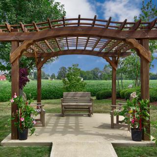 A wooden pergola with a bench surrounded by potted plants in a garden setting.