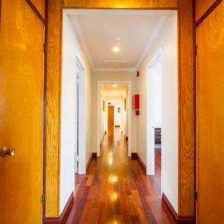 A brightly lit hallway with wooden floors and multiple doors.