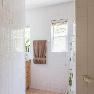 A bright and minimalist bathroom with natural light coming through the windows, featuring towels and tiled walls.