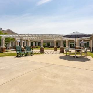 A spacious outdoor patio with tables, chairs, and a pergola on a sunny day.