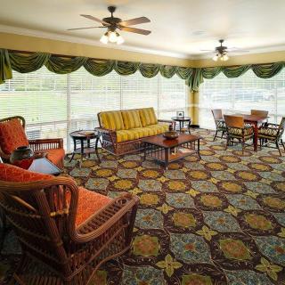 A spacious living room with wicker furniture and large windows allowing natural light to fill the space.