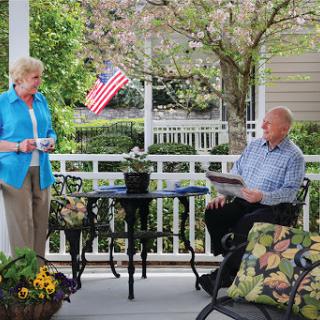A cheerful conversation on a sunny porch with an American flag in the background.