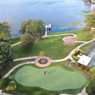 Aerial view of a scenic golf course by a tranquil lake, surrounded by lush greenery and winding pathways.