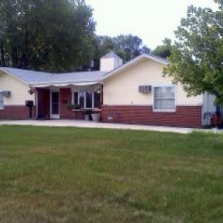 A single-story bungalow with a spacious yard and surrounding trees.