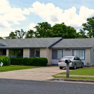 A suburban house with a driveway and car parked in front.