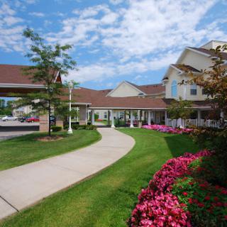 A welcoming entrance to a hotel surrounded by vibrant flowers and a clear blue sky.