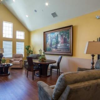 A spacious living room featuring comfortable seating, a large ornate painting, and natural light from multiple windows.