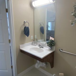 A clean and simple bathroom with a wall-mounted sink, mirror, and light fixture.