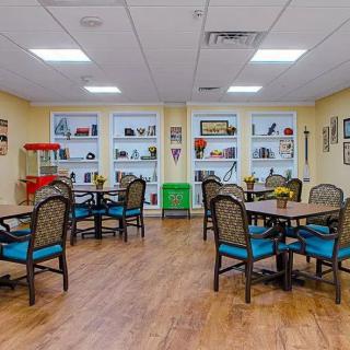 A well-organized room with tables and chairs, featuring bookshelves and various decorations.