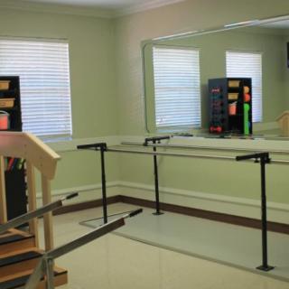 A rehabilitation room equipped with parallel bars and mirrors for physical therapy exercises.