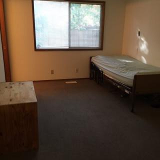 A minimalist bedroom with a single bed and a window.