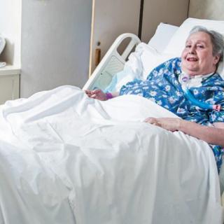 An elderly woman resting comfortably in a hospital bed.