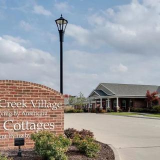 Entrance to a residential community with a brick sign and streetlight.