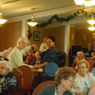 Elderly residents enjoying a dance at a nursing home event.