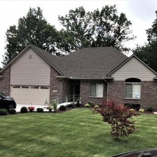 A suburban house with a well-maintained lawn and surrounding trees.