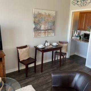Cozy dining area with a small table and chairs, featuring artwork and an open view into the kitchen.