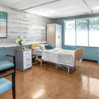 A clean and well-organized hospital room with a single bed and large windows.
