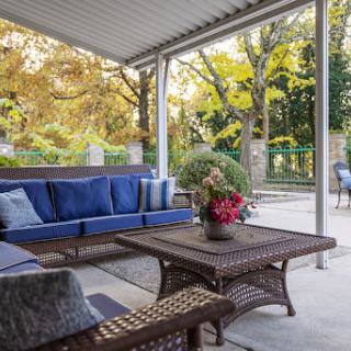 A cozy outdoor patio area adorned with comfortable blue seating and a beautiful floral centerpiece, perfect for enjoying the autumn scenery.