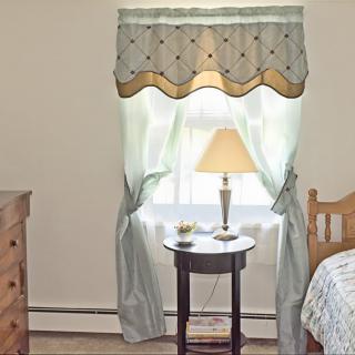 A cozy bedroom with a lamp on a small round table by the window.