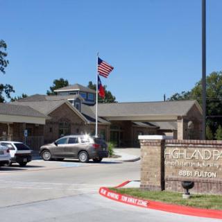 A view of a building with flags, featuring a parking lot and sign.