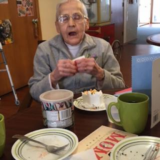 An elderly individual enjoying a dessert at the dining table.