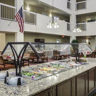 A well-lit indoor buffet area with a salad bar, featuring an American flag in the background.