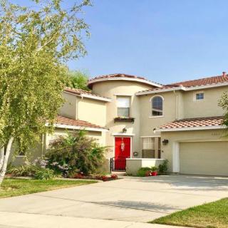 A modern two-story house with a red door and a well-maintained front yard.