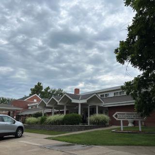 A residential building under a cloudy sky with a parked car.