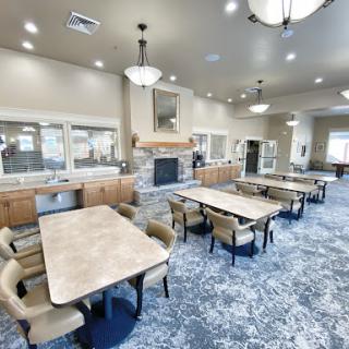 A cozy community dining area featuring several tables and comfortable seating, designed for social gatherings.