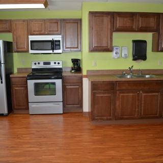 A modern kitchen with wooden cabinets, stainless steel appliances, and green walls.