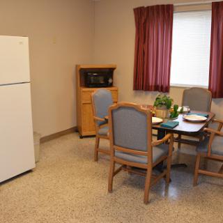 A cozy kitchen and dining area featuring a refrigerator, microwave, and a small table set for meals.