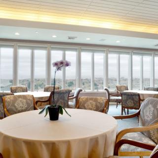 A spacious indoor dining area with large windows and elegant table settings.