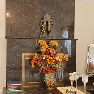 A well-decorated fireplace with a floral arrangement, books, and elegant glassware.