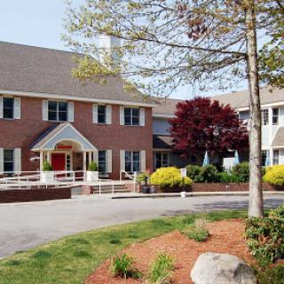 A charming residential building surrounded by lush greenery and colorful flowers.