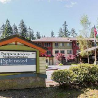 An exterior view of the Evergreen Academy Montessori School near the Spiritwood apartment complex, surrounded by trees.
