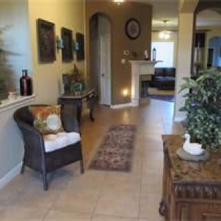A cozy and elegantly decorated living room hallway with a chair, plants, and artwork.