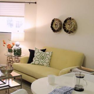 A cozy living room with a yellow sofa, decorative pillows, and wall art.