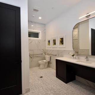 A sleek and modern bathroom featuring marble walls, contemporary fixtures, and stylish lighting.