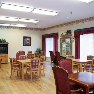 A cozy dining area with wooden tables and upholstered chairs, illuminated by ceiling lights.