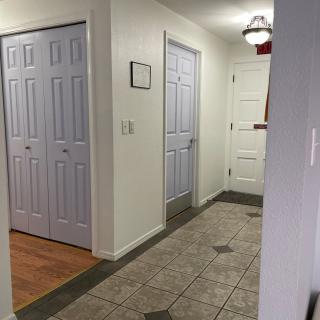 A hallway with tile flooring and several closed doors.