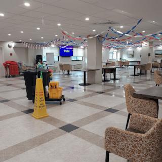 A spacious indoor cafeteria area featuring cleaning equipment and empty tables.