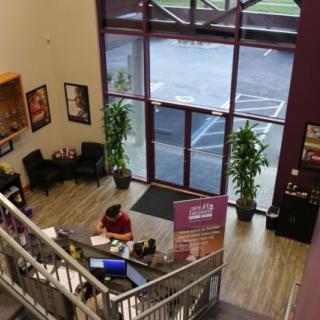 The image shows the lobby area of a gym, featuring a reception desk and posters on the walls.