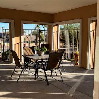 A cozy outdoor patio area with a table and chairs, bathed in warm sunlight.
