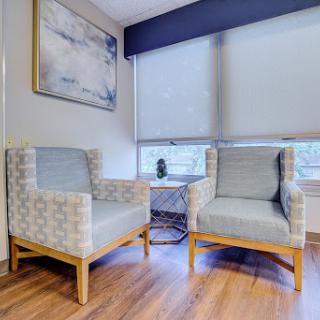 A cozy seating area featuring two modern chairs and a piece of artwork on the wall.