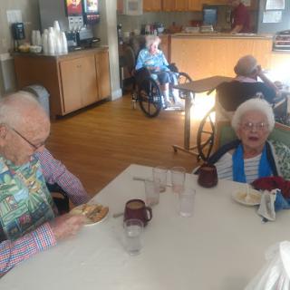 Elderly residents enjoying a meal together in a care facility.