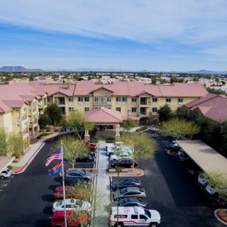 Aerial view of a large building complex with a parking lot and flags at the entrance.
